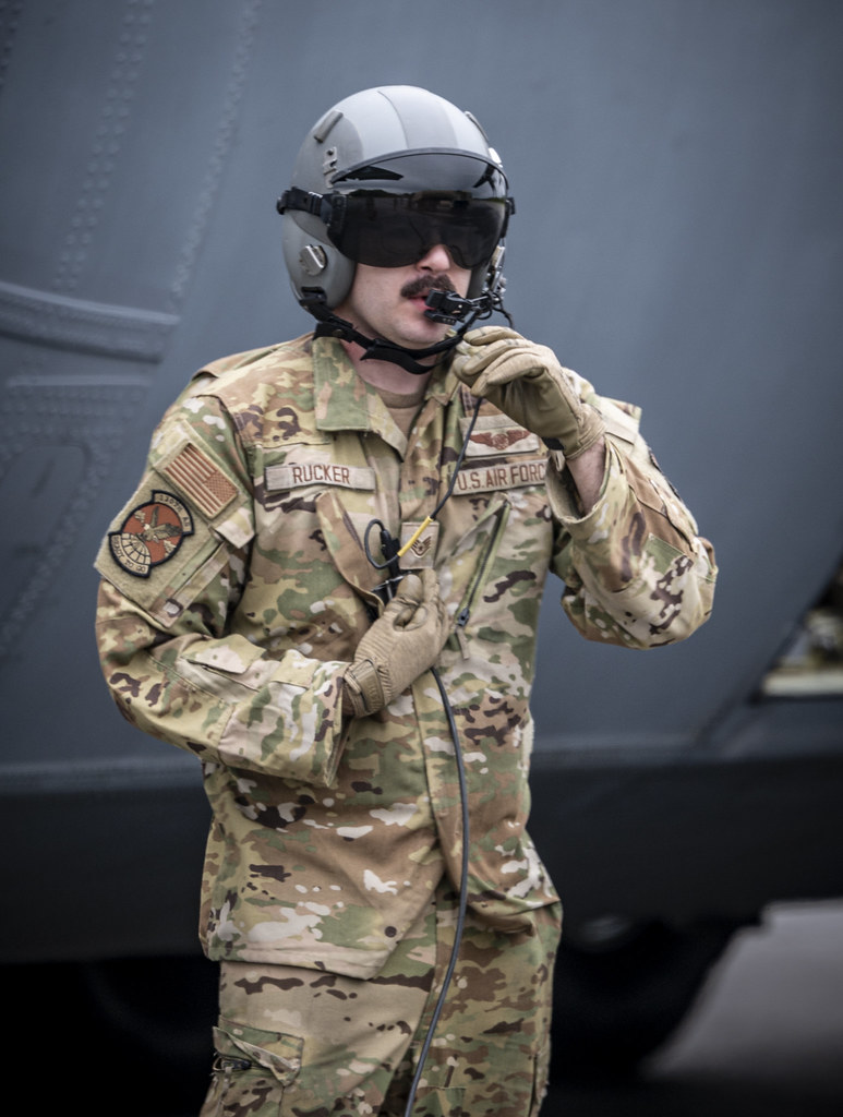 abd hava kuvvetleri pilotu kamuflaj üniforma ve kask ile uçak önünde görevde