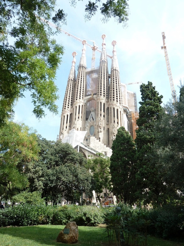Ağaçların arasından yükselen Barselona Sagrada Familia bazilikası görünümü