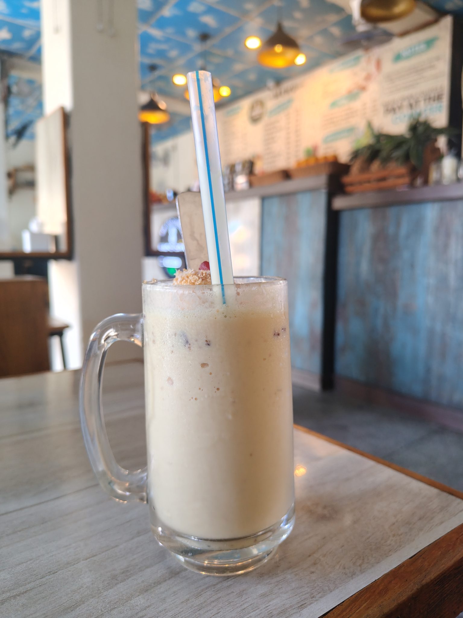 Ahşap Kafe Masasında Cam Kupta Taze Muzlu Smoothie ve Sıcak Atmosfer