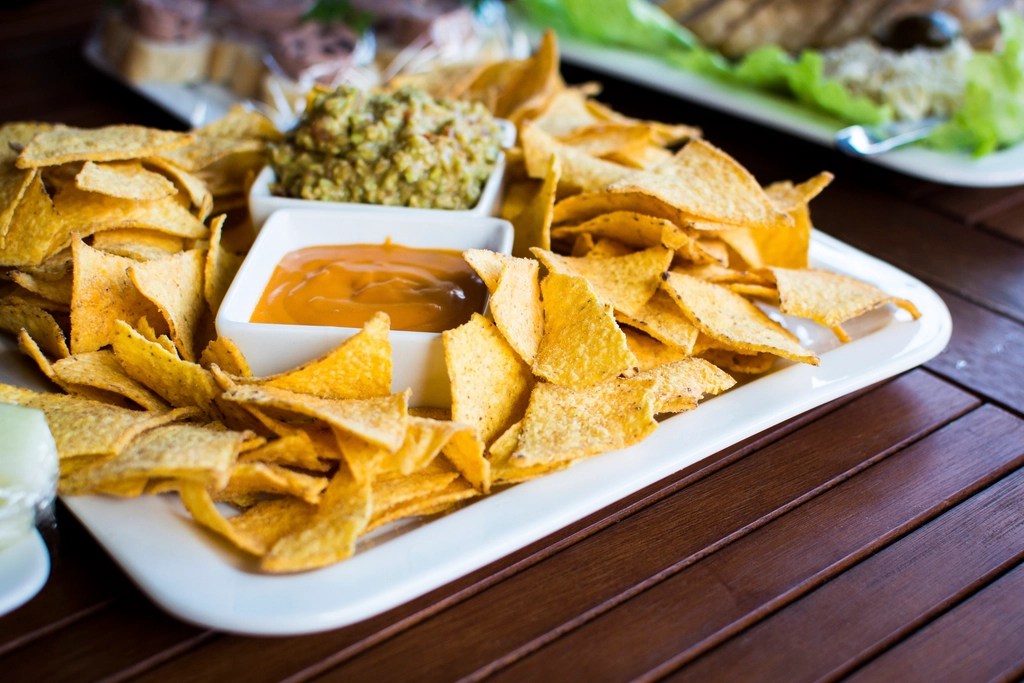 Ahşap masada çıtır nachos, guacamole ve salsa sosuyla enfes sunum