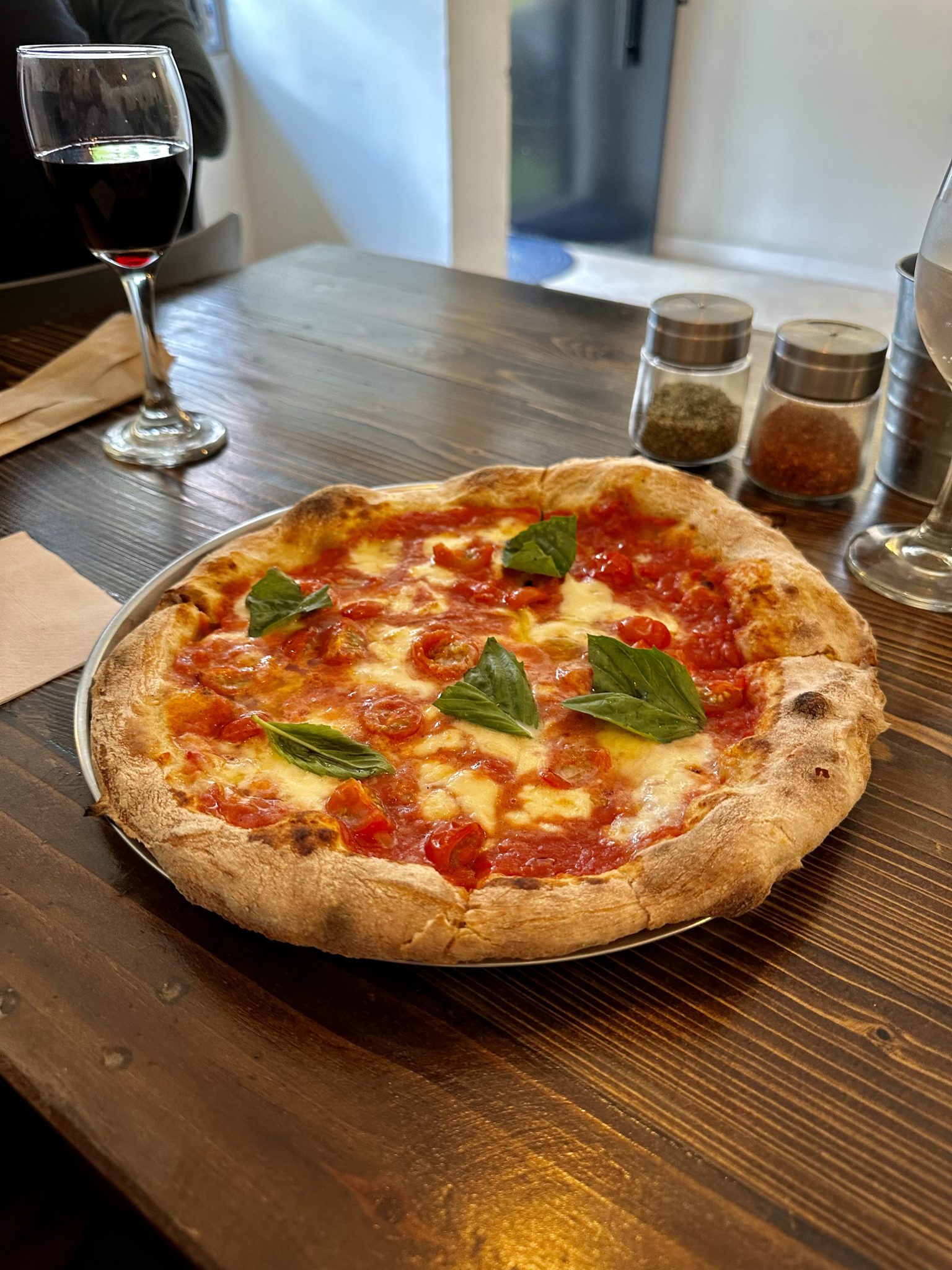 Ahşap Masada Taze Fesleğenli İtalyan Pizzası ve Kırmızı Şarap Eşliğinde Lezzet Anı