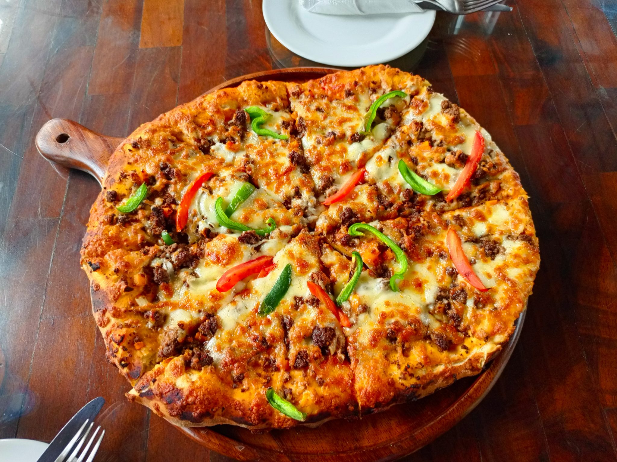 Ahşap sunum tahtasında kıymalı renkli biberli bol peynirli nefis pizza tabağı