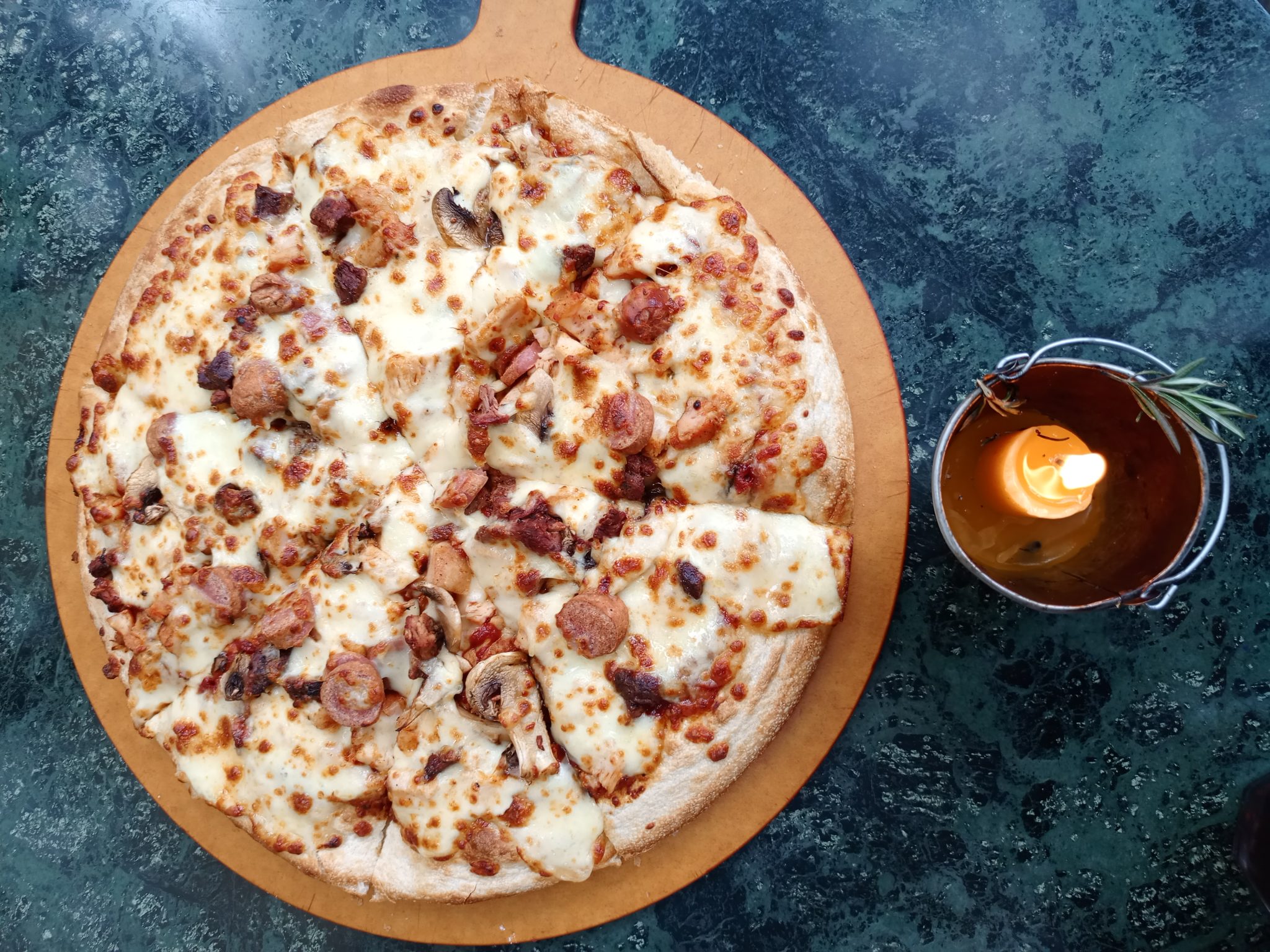 ahşap tepsi üzerinde nefis mantarlı sucuklu pizza sunumu ve mum ışığı