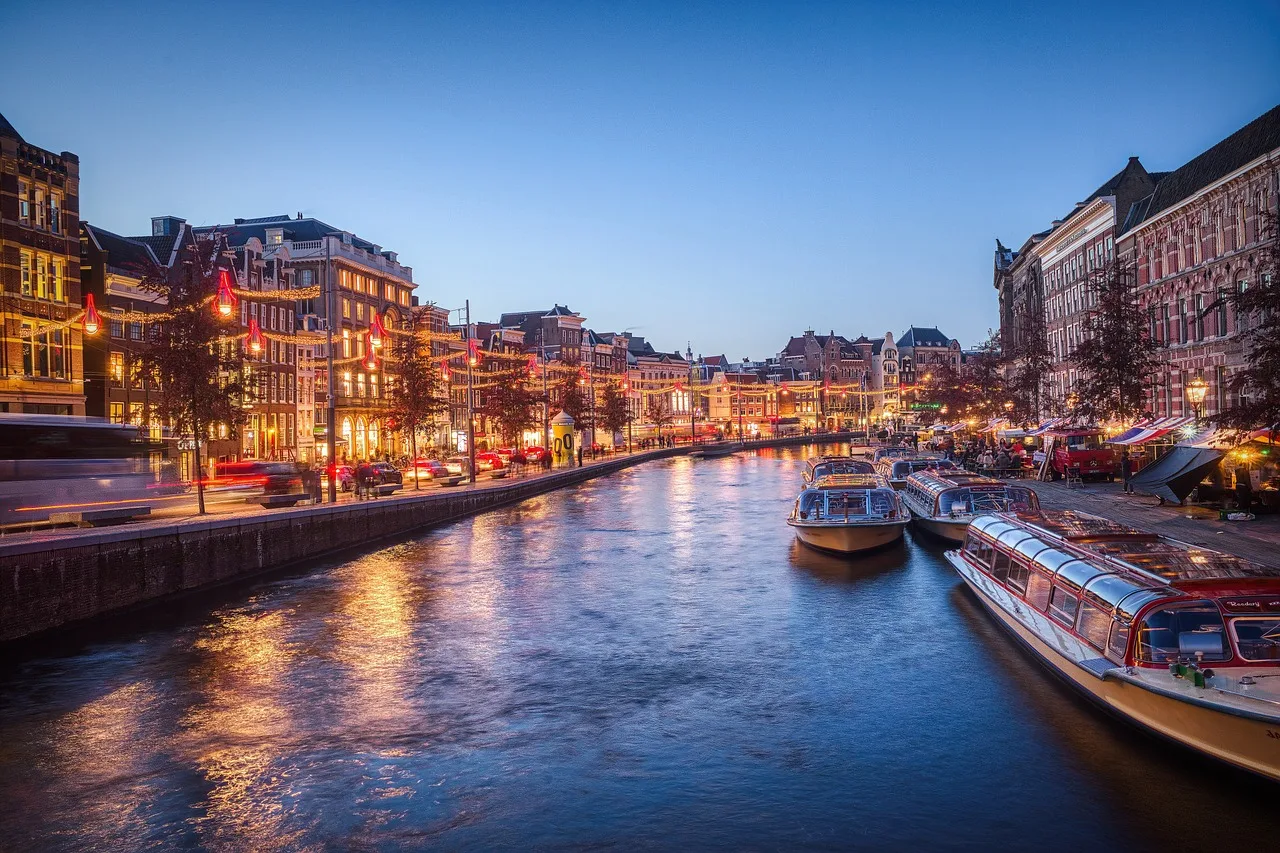 Amsterdam kanalında akşam ışıkları ve yansıyan şehir silüeti