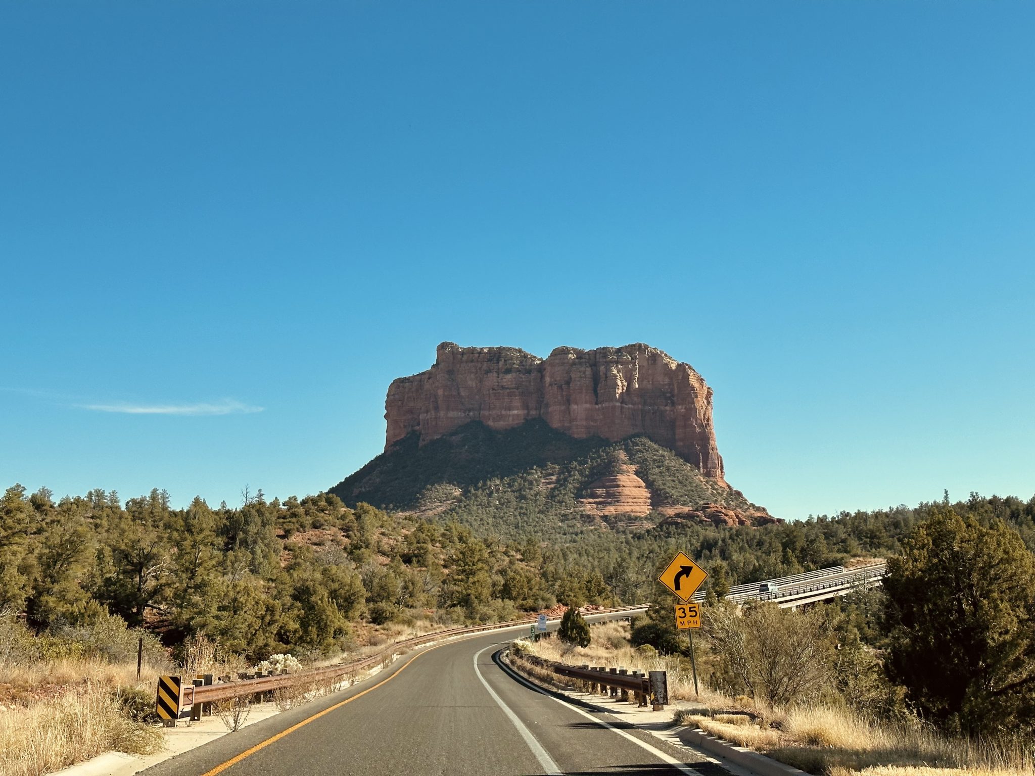 Arizona Sedona'da Mavi Gökyüzü Altında Kırmızı Kaya Oluşumları ve Virajlı Yol
