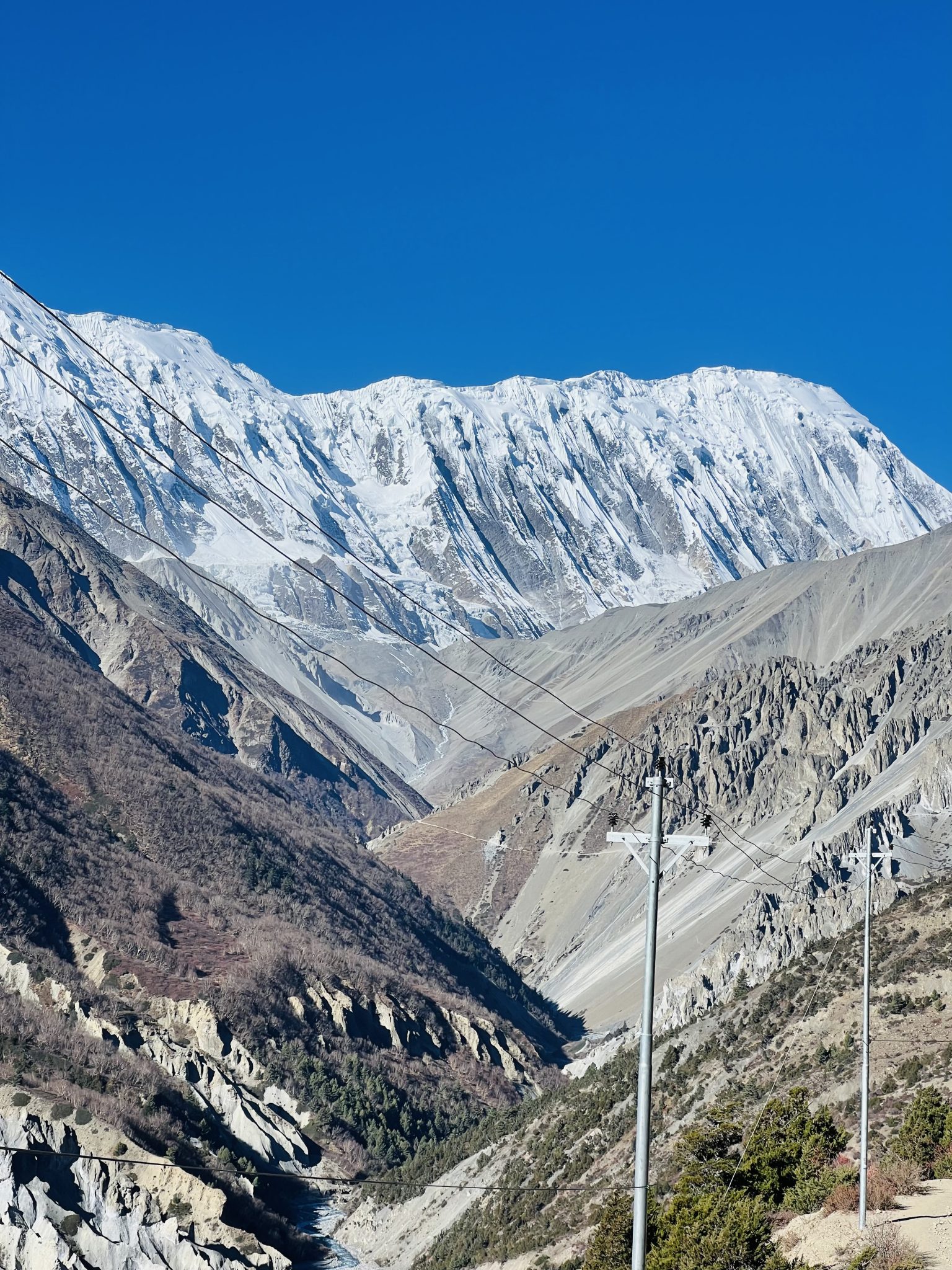 Berrak mavi gökyüzü altında karlı zirveli dağların muhteşem panoramik görüntüsü