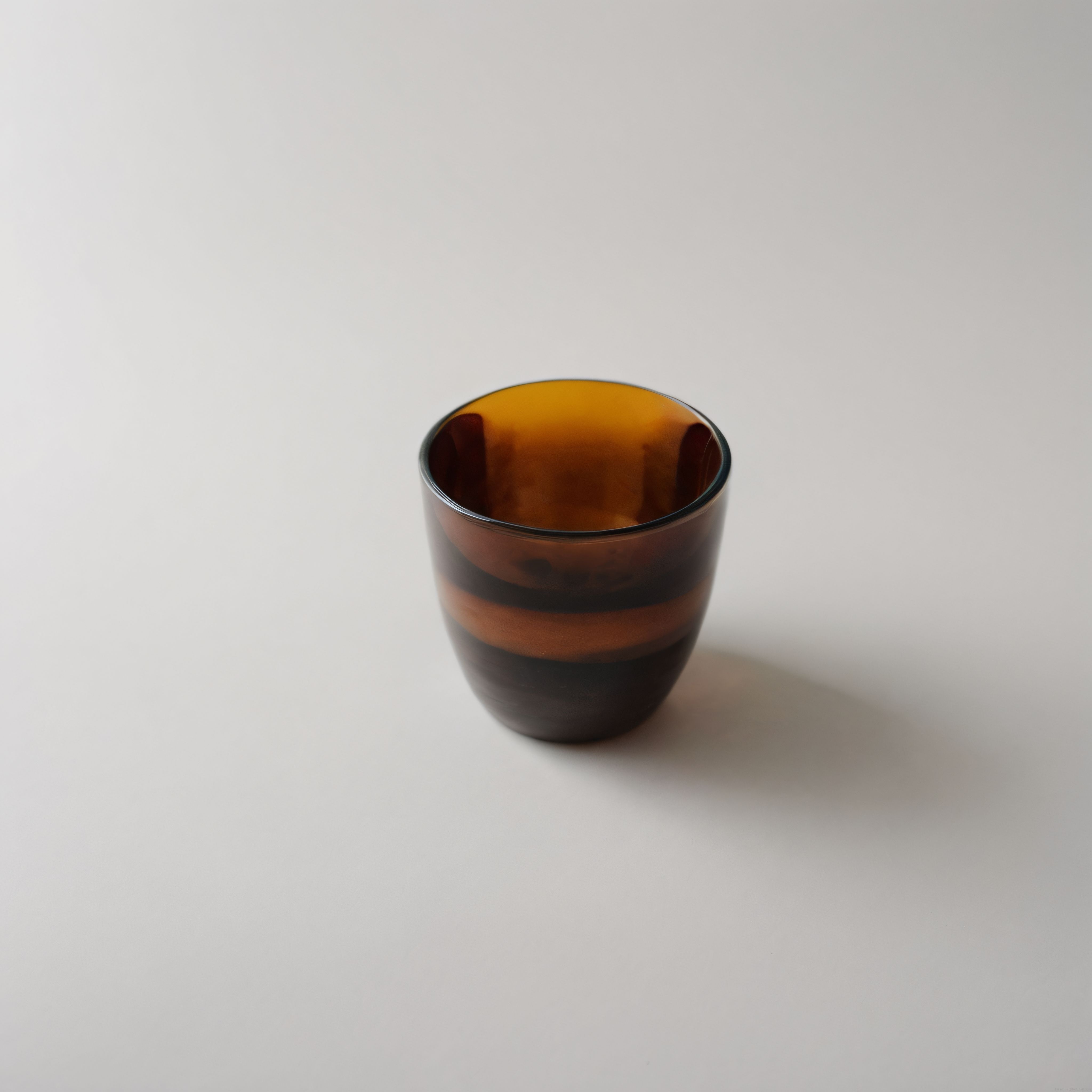 Beyaz arka planda minimalist amber rengi dekoratif cam bardak detayı