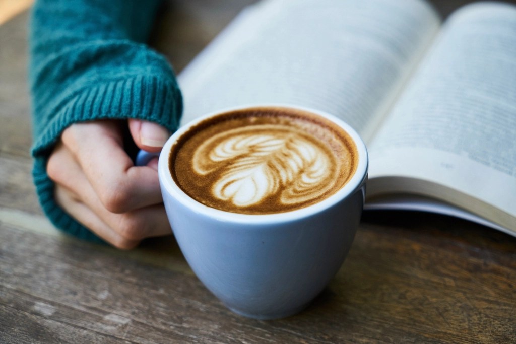 Beyaz Fincanda Kalp Desenli Latte Art ve Açık Kitapla Sıcak Anlar