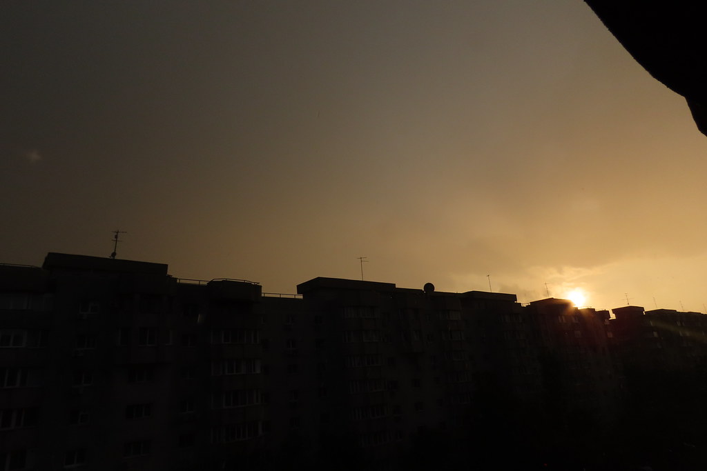 bina siluetleri arasından süzülen gün batımı ışığı ve sisli şehir manzarası