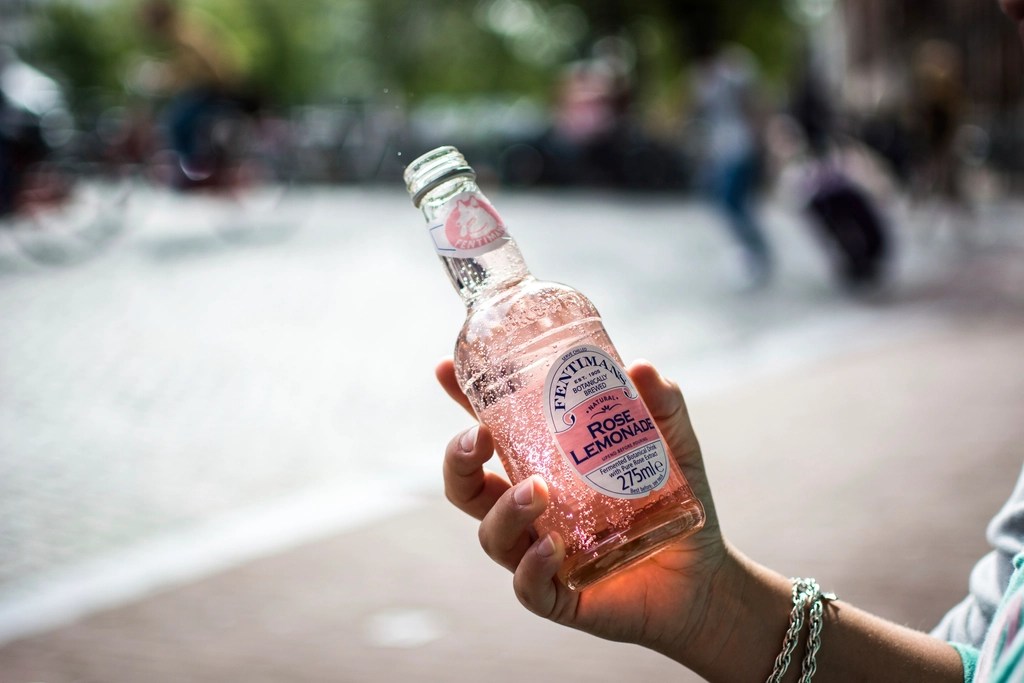 Bir Elde Gül Aromalı Pembe Limonata Şişesi ve Yaz Günü Serinletici Anlar
