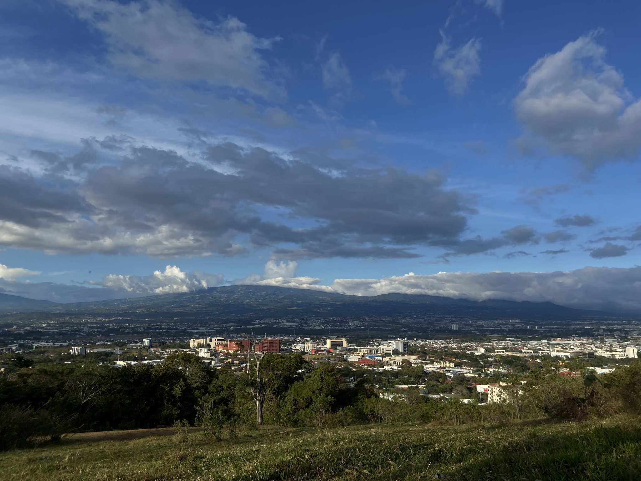 Bulutlu Mavi Gökyüzü Altında Yeşil Tepeden Şehir ve Dağ Panoraması