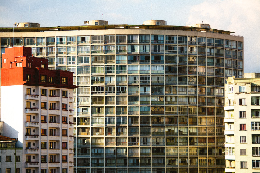 Büyük Şehirdeki Yuvarlak Cam Cepheli Apartman ve Kırmızı Çatılı Bina