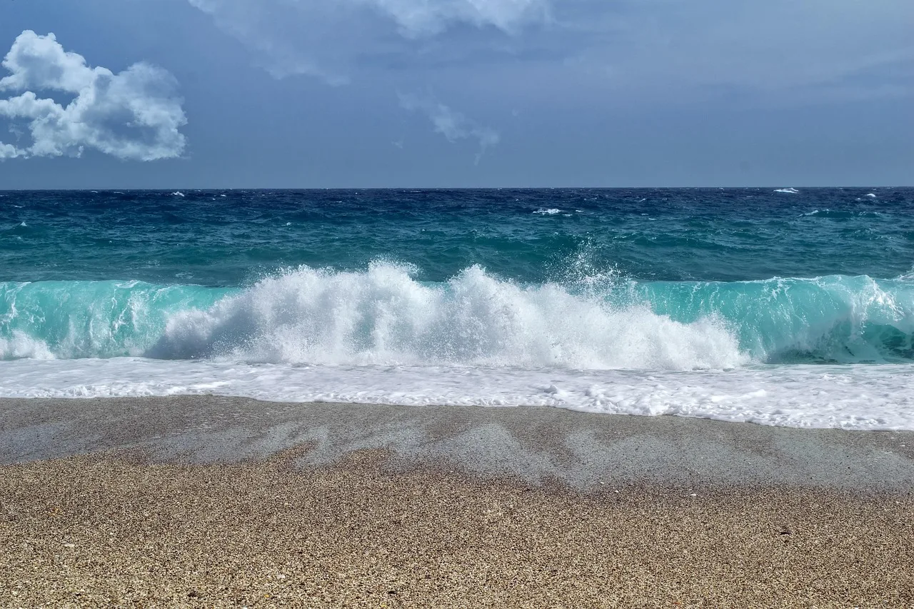 Dalgalı deniz kıyısında kumlu plaj manzarası