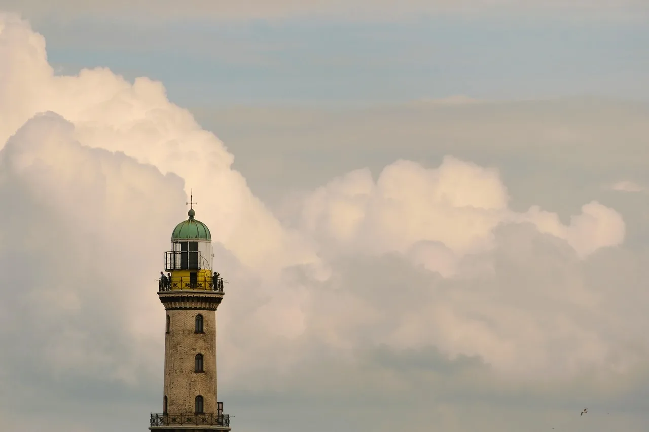 Deniz feneri ve bulutlu sahil manzarası
