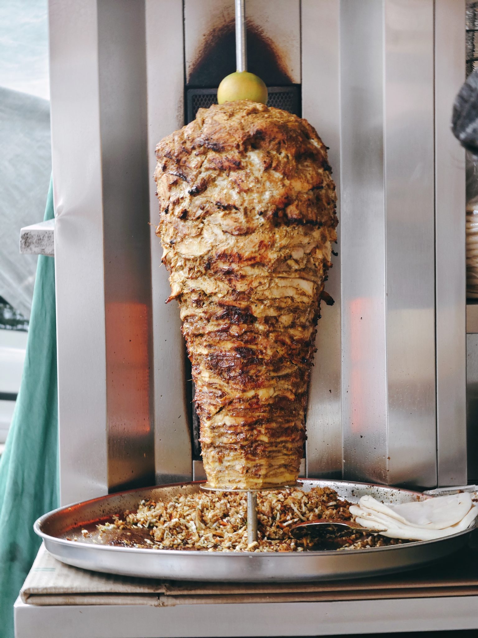 Dikey döner makinesinde kızaran kebap, üstünde zeytin ve tepside dilimlenmiş et