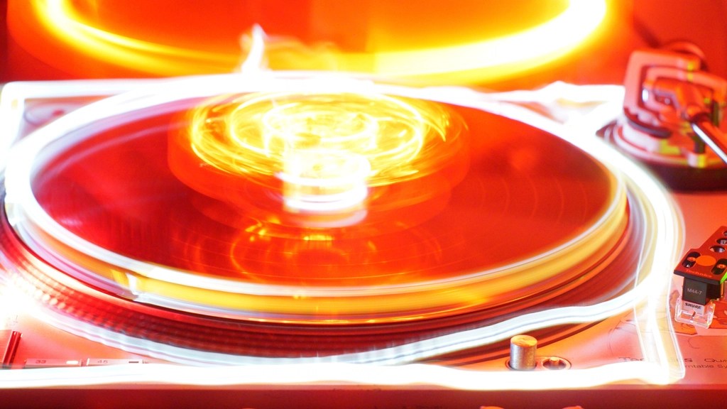 Dönen vinil pikap plağı ve sıcak turuncu ışıkların estetik müzik anı