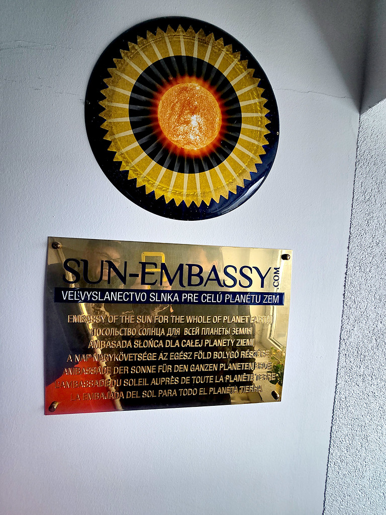 Dünya'nın Güneş Büyükelçiliği: Beyaz Duvar Üzerindeki Metal Sun Embassy Tabelası