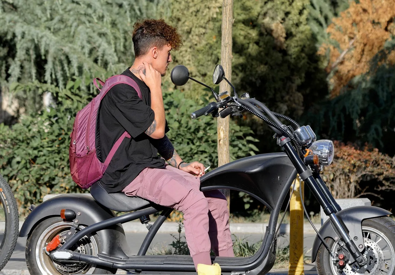 Elektrikli motosikletli genç adam sokakta