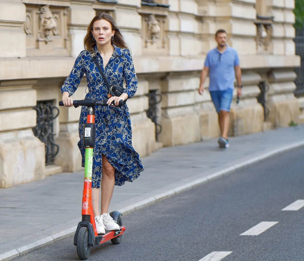 Elektrikli scooter ile sahilde yürüyen genç kız