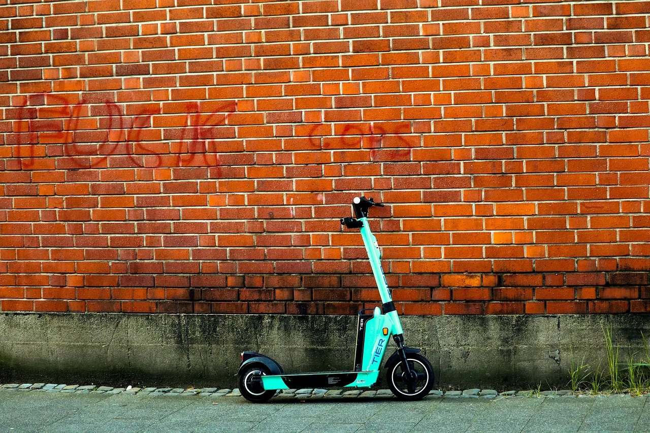 Elektrikli scooter kırmızı duvar önünde şehir mobilitesi
