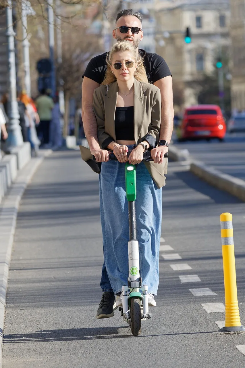 Elektrikli scooter'lı genç çift yürüyüşü - şehir sokakları