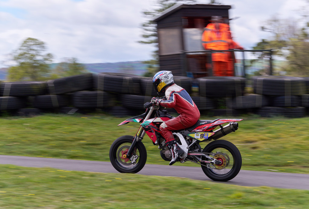 Enduro motosikletiyle yarış pistinde hız yapan kasklı sürücünün aksiyon dolu anı