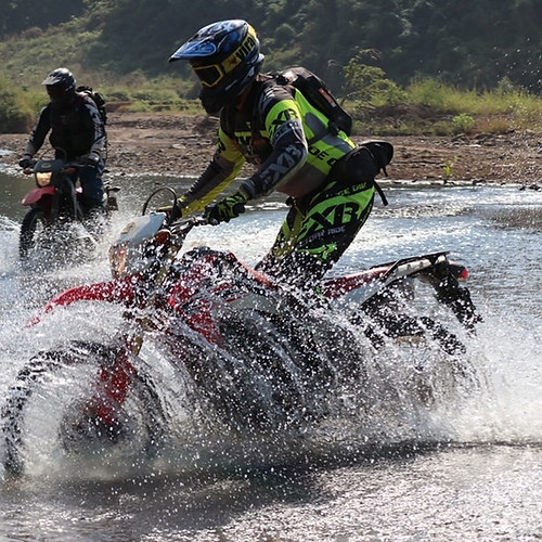 enduro motosikletlerle nehir geçişi yapan kasklı sürücülerin aksiyon anları