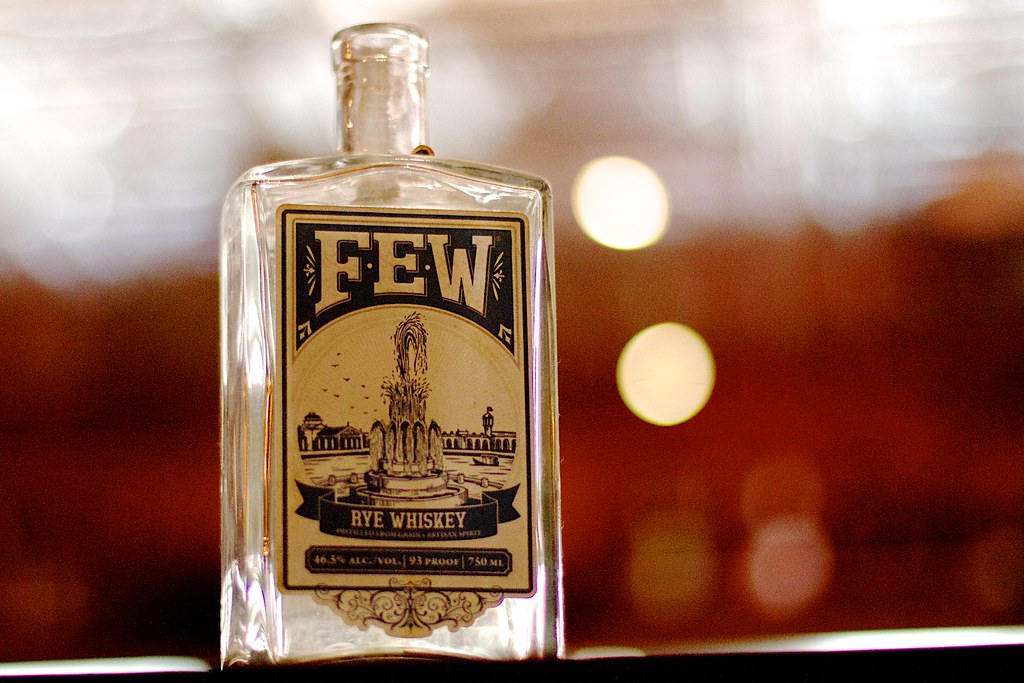 FEW Rye Whiskey Şişesi, Vintage Etiket ve Sıcak Bar Ortamı Detay Görseli