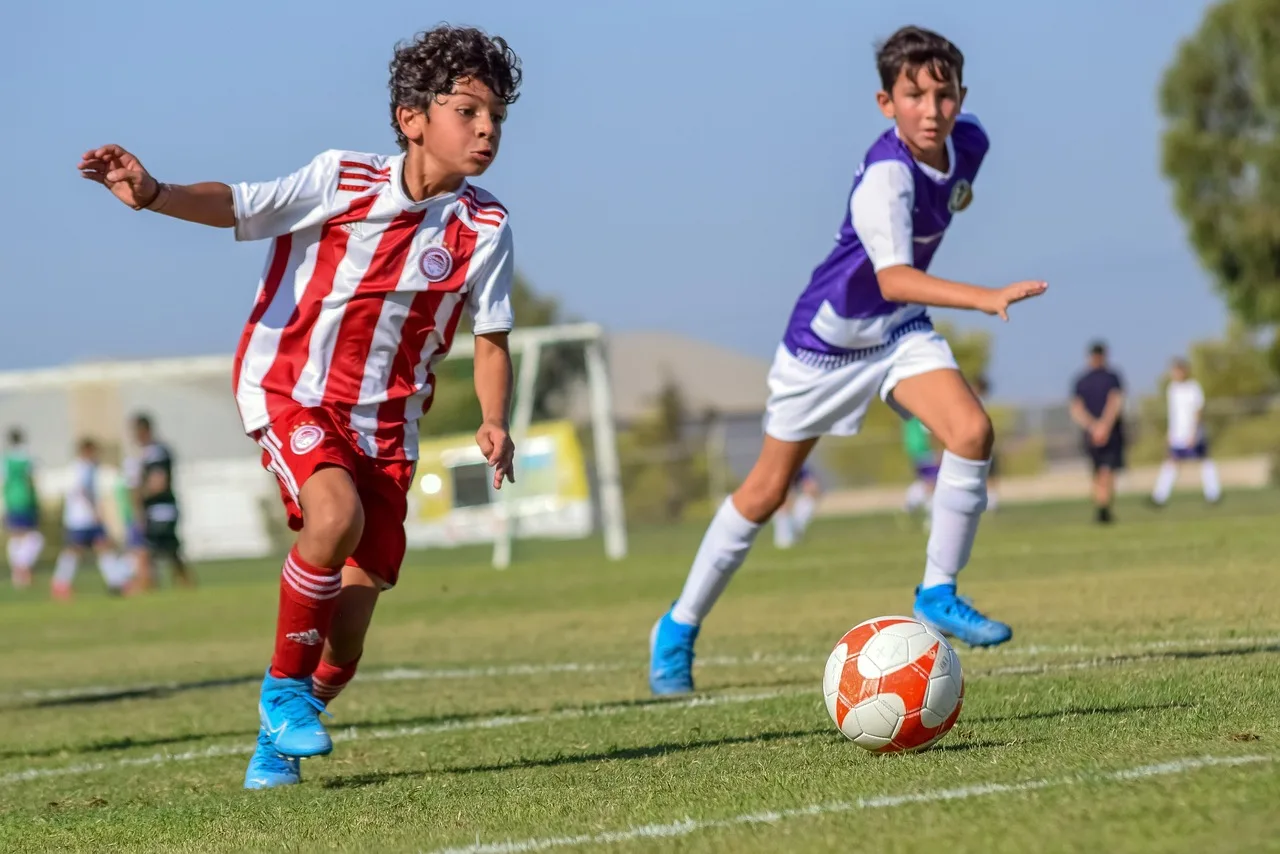 Futbol topu ile koşan çocuklar - yeşil saha