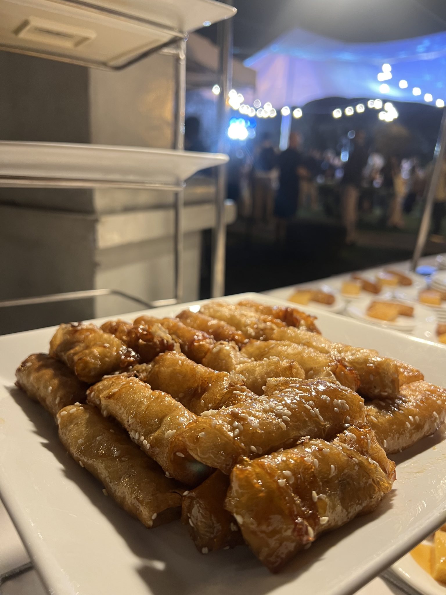 Gece Davetinde Susamlı Çıtır Baklava Sunumu ve Işıklı Açık Hava Atmosferi