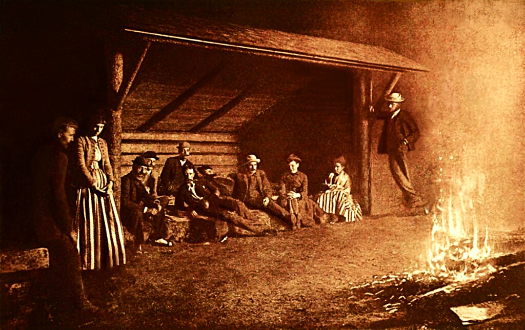 Gece vakti ateş başında toplanmış sepia tonlamalı tarihi grup