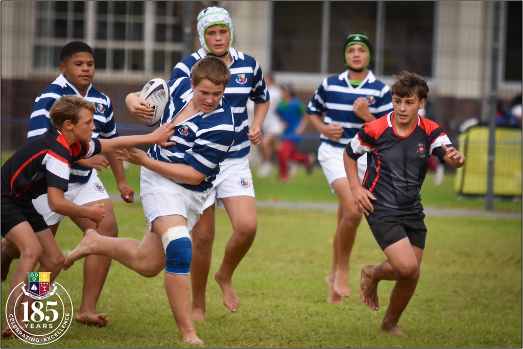 Genç rugby oyuncularının çim sahada hızla atak yaptığı an ve takım mücadelesi
