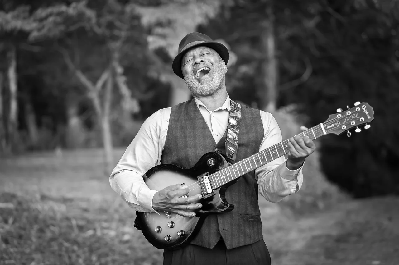 Gitarist portresi orman içinde mutlu şarkı söyleyen