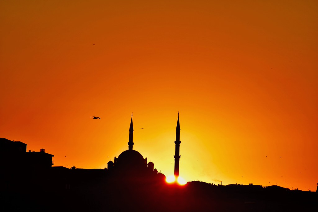 Gün Batımında İstanbul Silueti: Cami Minareleri ve Turuncu Gökyüzünde Kuş