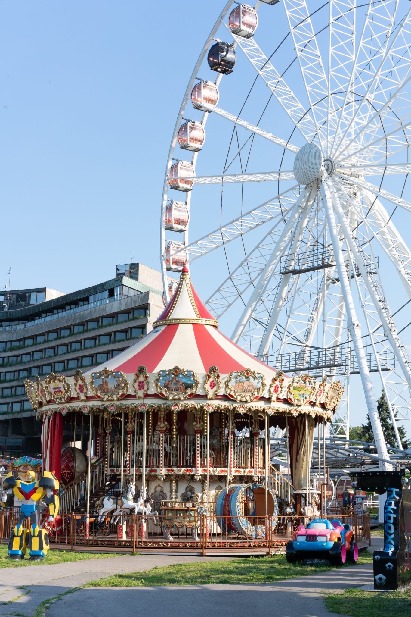 güneşli havada dev dönme dolap ve süslü atlıkarıncanın olduğu renkli lunapark