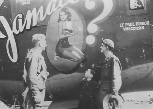 İkinci dünya savaşı dönemi uçağın burnundaki pin-up sanatına bakan askerler