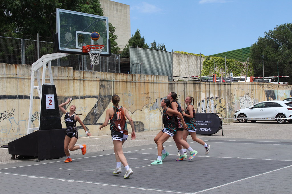 Kadın basketbolcular potaya atış yaparken takım arkadaşları ribaundu bekliyor