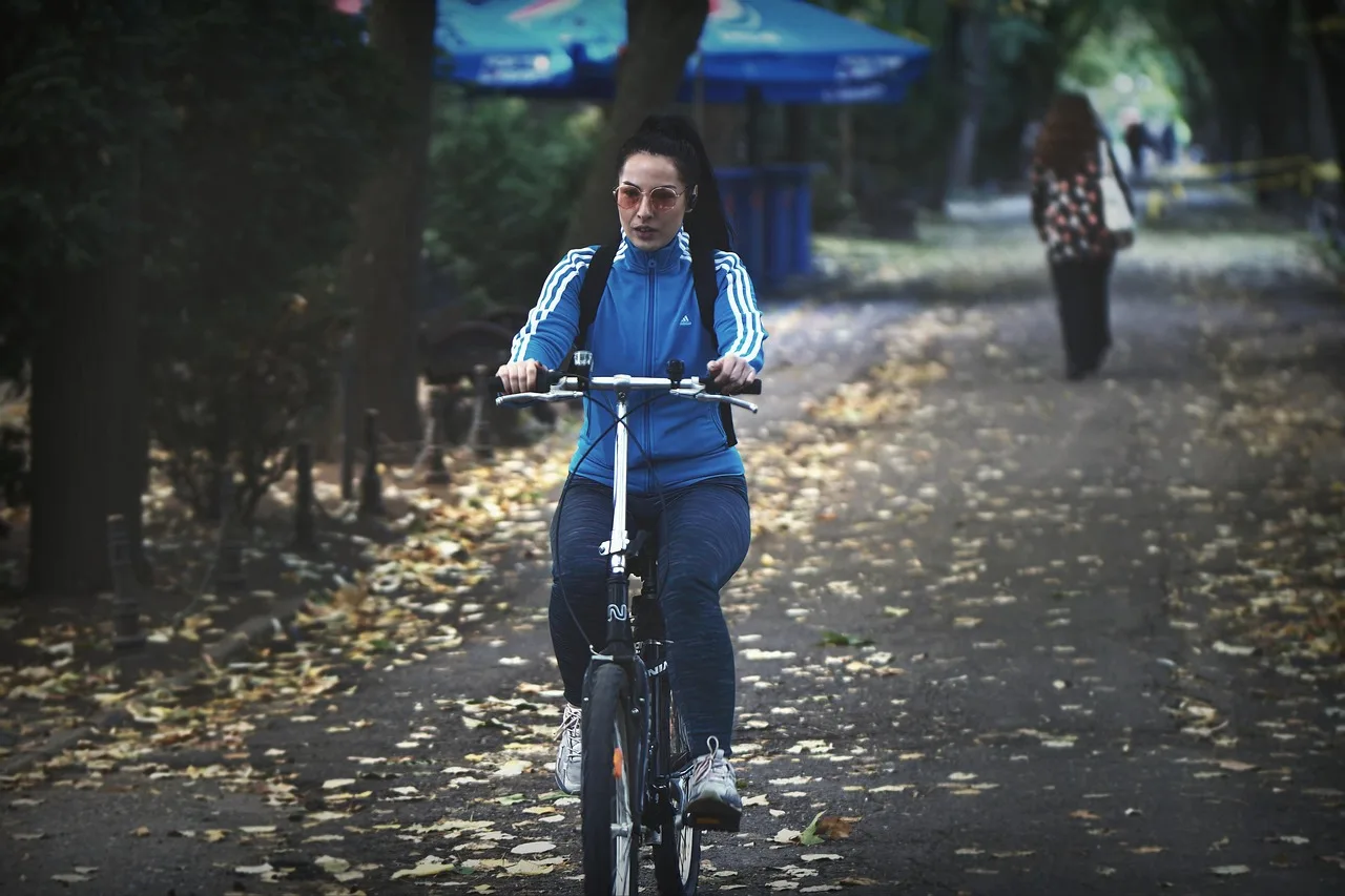 Kadın bisikletçi akşam parkında sonbahar yürüyüşü