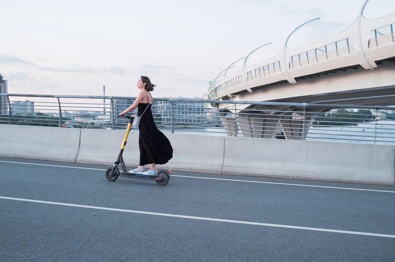 Kadın elektrikli scooter'ı şehir sokaklarında
