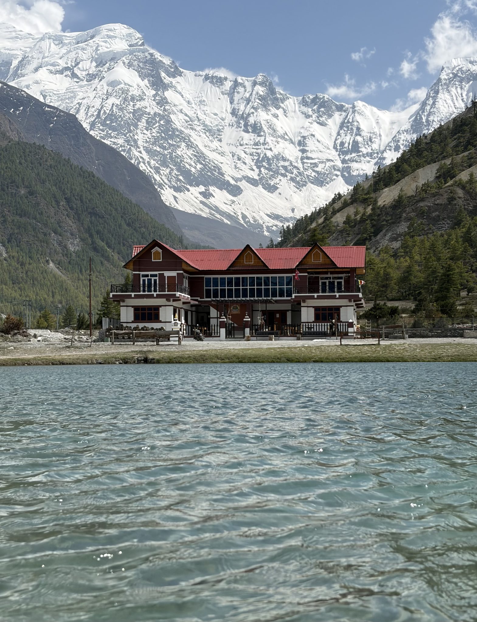 Karlı dağların eteğinde göl kıyısındaki ahşap otel ve büyüleyici doğa manzarası