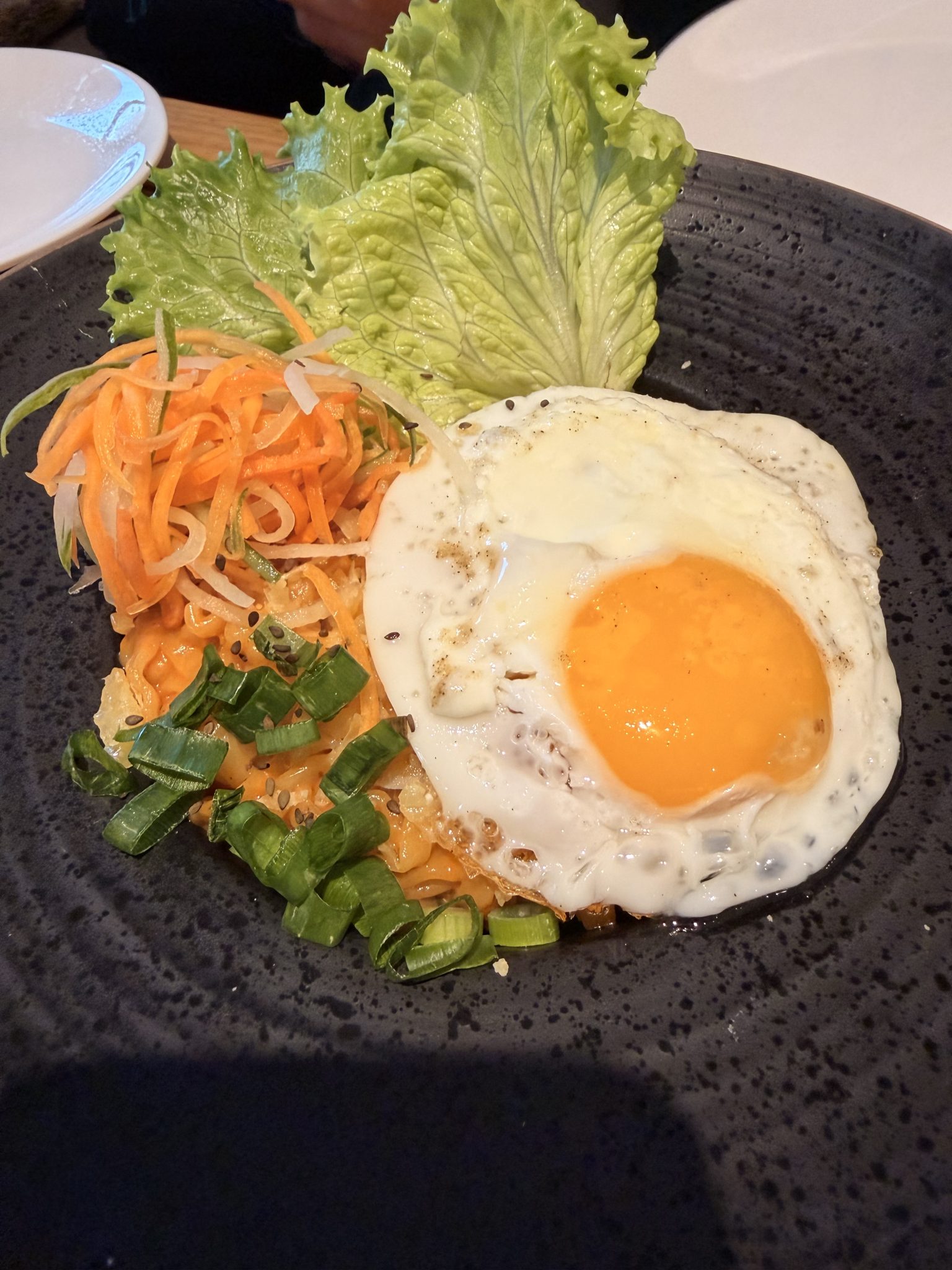 Kızarmış yumurtalı, baharatlı noodle kasesi: Taze havuç ve yeşil soğanla renkli Asya mutfağı