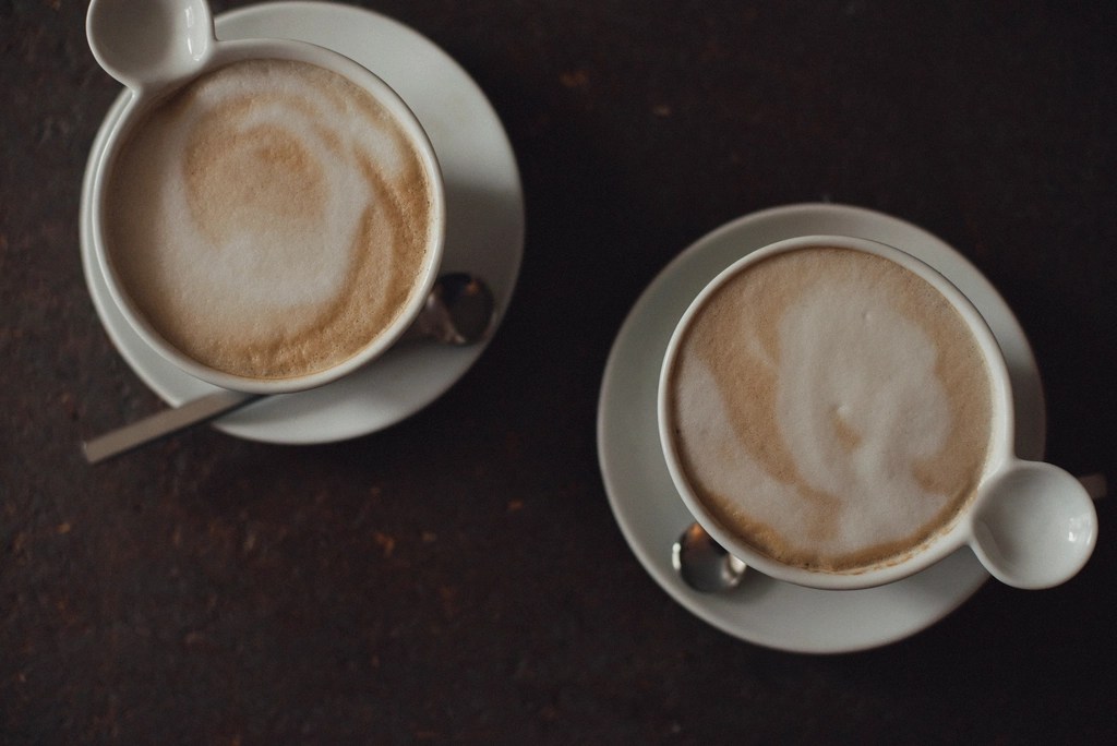 Koyu Ahşap Masada Üstten Çekilmiş İki Fincan Köpüklü Latte Kahve