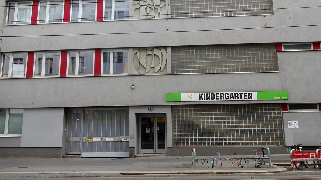 Kreş binasının gri cephesi, kırmızı pencere şeritleri ve sokak görünümü Kreş binasının gri cephesi, kırmızı pencere şeritleri ve sokak görünümü