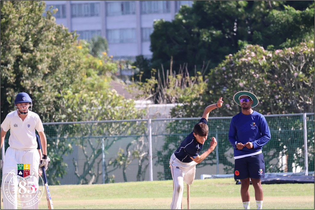 Kriket maçında genç bowler atış yaparken, hakem ve batsman sahada pozisyon aldı