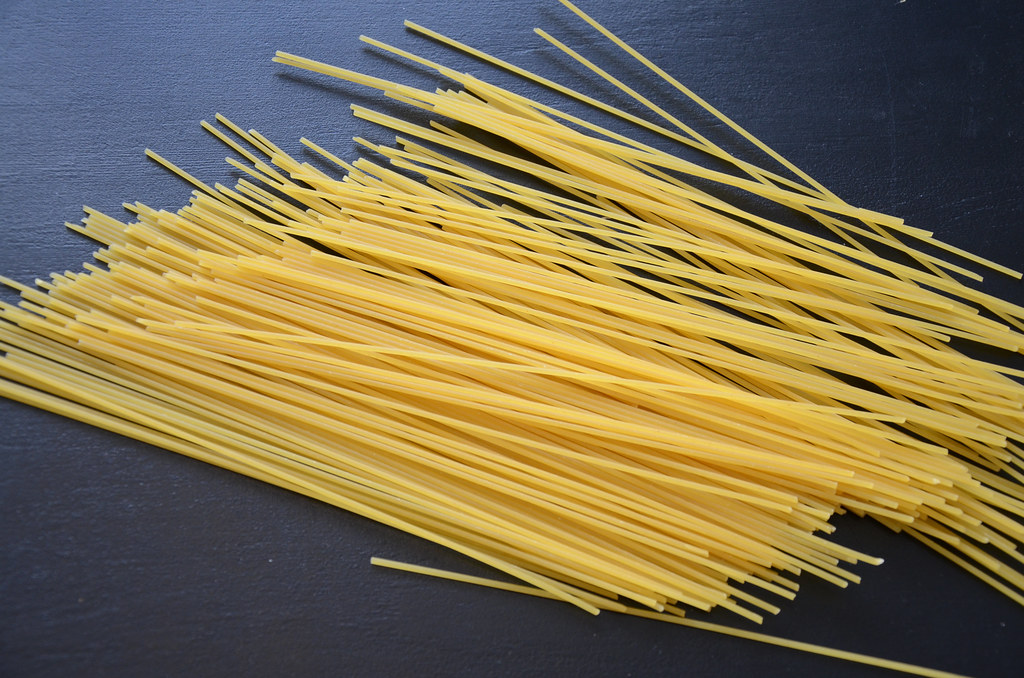 Lacivert zemin üzerinde dağılmış pişmemiş sarı spagetti makarna fotoğrafı