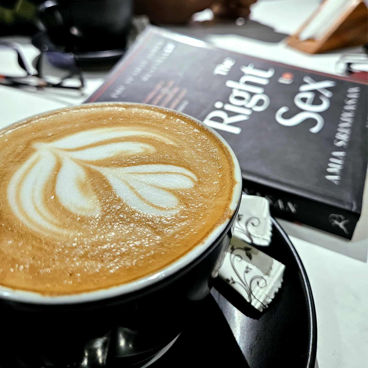 latte art süslemeli kahve ve yanındaki kitapla keyifli bir kafe molası