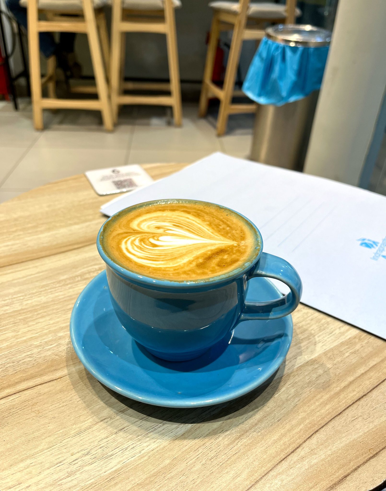 Mavi Fincanda Latte Art ile Süslenmiş Sıcak Kahve ve Kafe Ortamı
