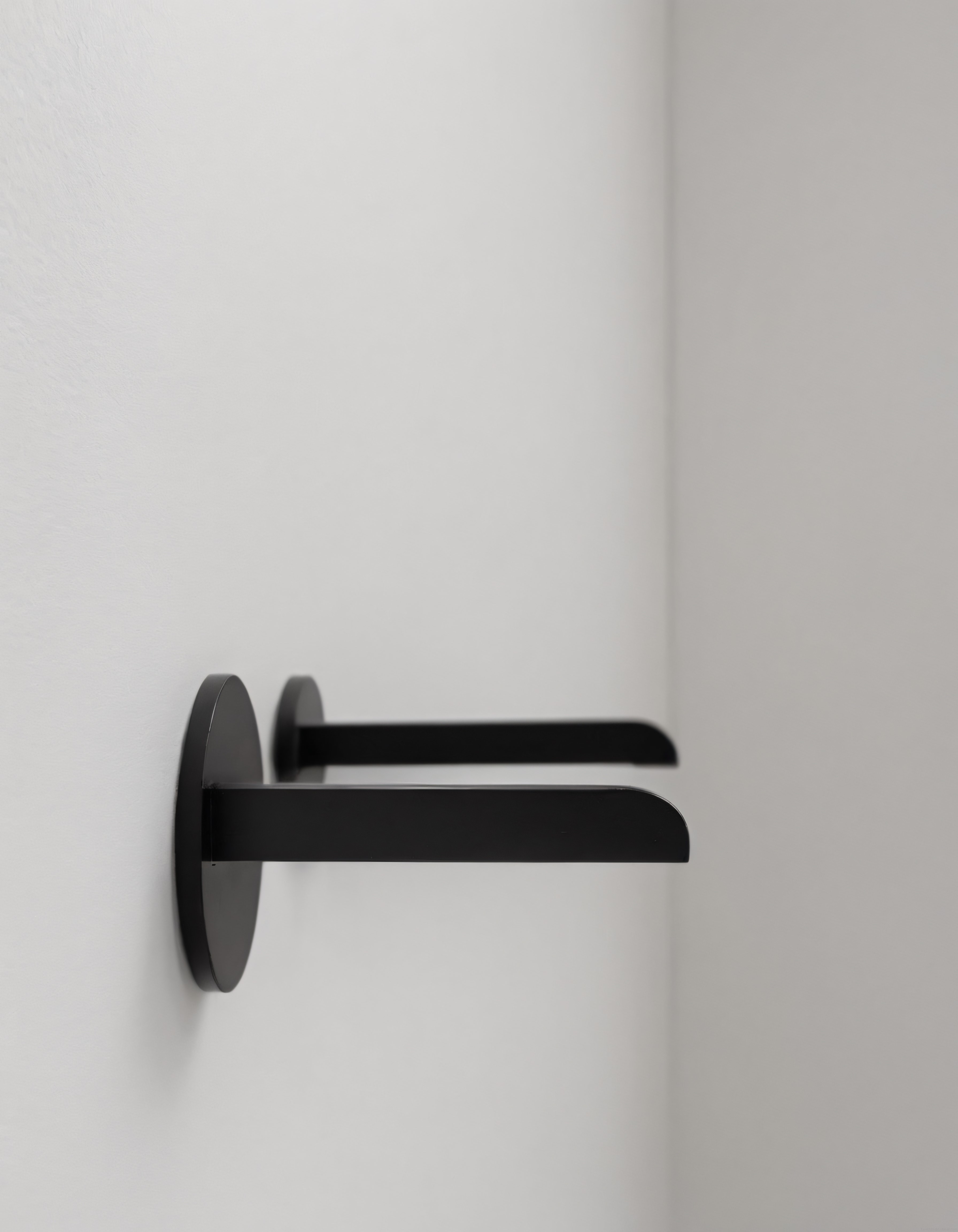 Minimalist iç mekanda beyaz duvar üzerindeki modern siyah kapı kolu detayı