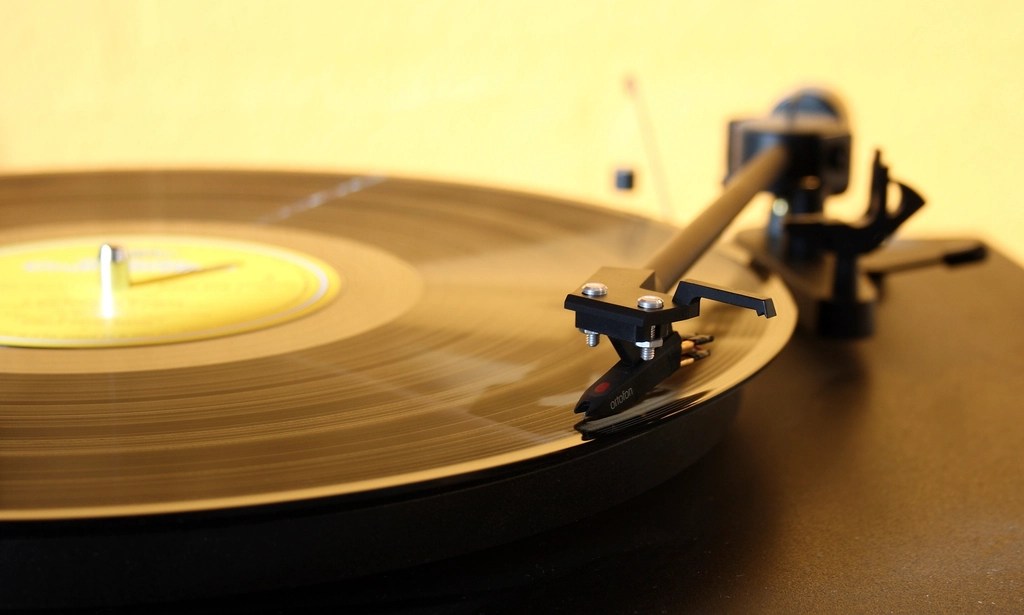 Nostaljik Müzik Atmosferi: Sarı Işık Altında Dönen Vinil Pikap Görseli