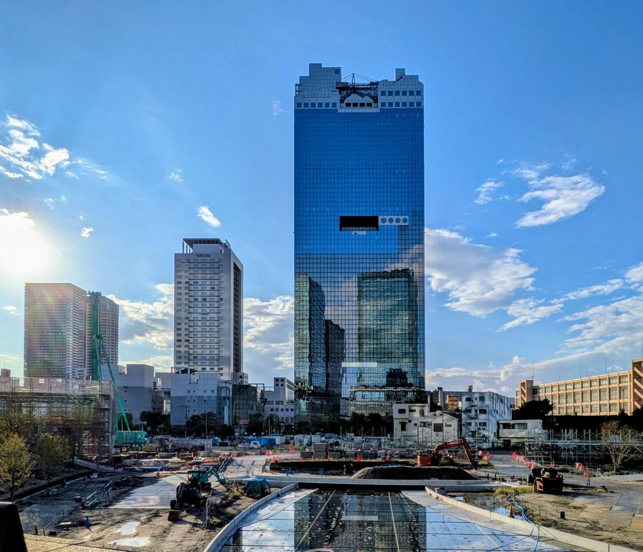 Osaka'nın simgesel cam gökdeleni, parlak güneşli mavi gökyüzü ve kentsel dönüşüm